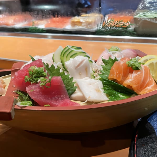 A House of Japan sashimi boat with tuna, salmon, and white fish, garnished with cucumber and lemon.